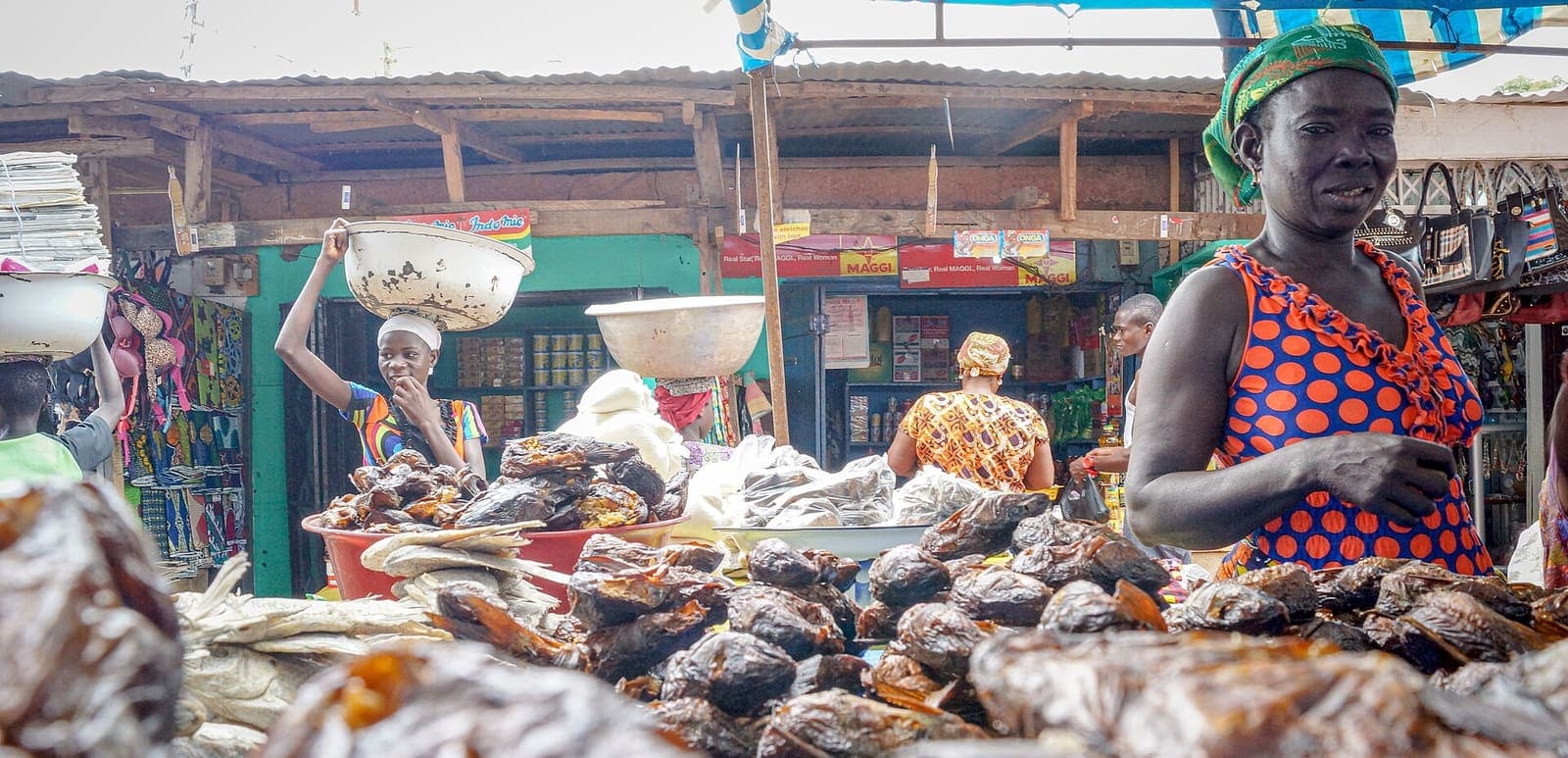 A smiling trader stands behind her display of smoked fish at a market in Ghana.